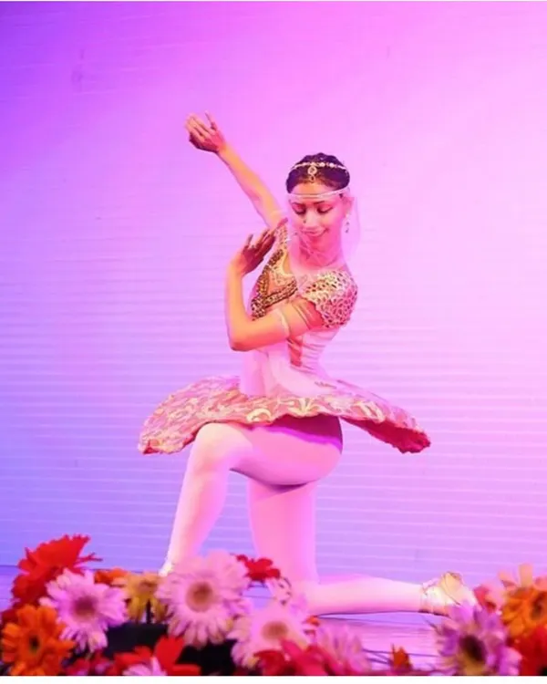 A solo performance from a classical ballet production, surrounded by flowers. The stage has always been a special place for me, and I use my experience as a professional ballerina to guide my students in their own artistic expression.