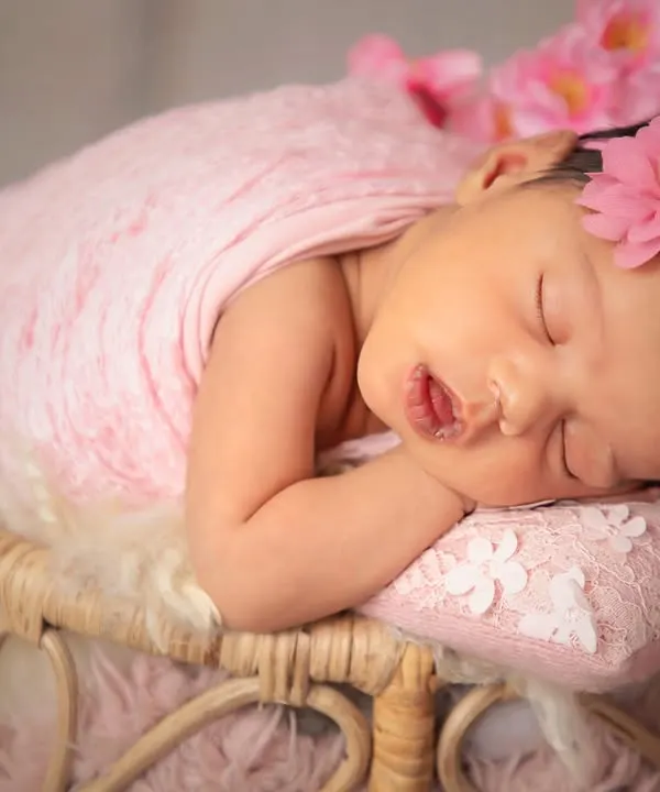 Prettiness in pink. A classic newborn portrait featuring a soft pink wrap, a delicate floral headband, and a peacefully sleeping baby. This style is timeless and always beautiful.
