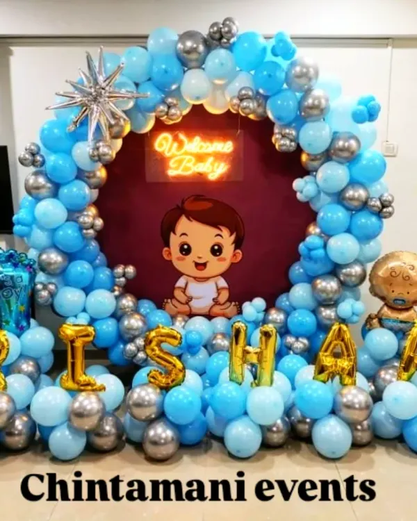 A grand 'Welcome Baby' decoration for a baby boy. The circular backdrop is filled with blue and silver balloons and features the baby's name in foil letters, creating a beautiful focal point for welcoming the newborn home.