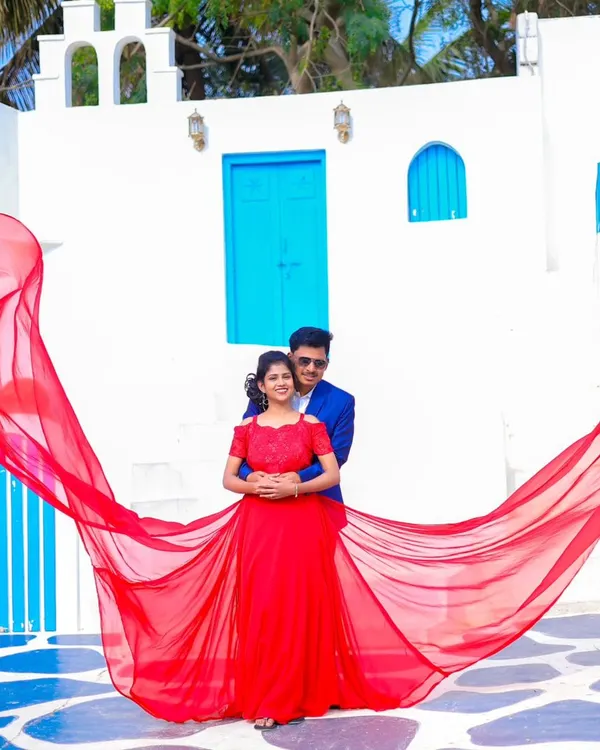 A dramatic shot using a flowing red gown against a beautiful Santorini-themed backdrop. My packages include a variety of gowns like this to make your pre-wedding photos truly stand out.