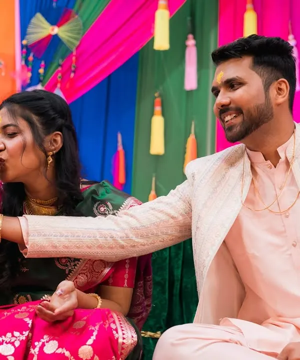 A playful moment from a pre-wedding ceremony, as the groom helps the bride with a ritual.