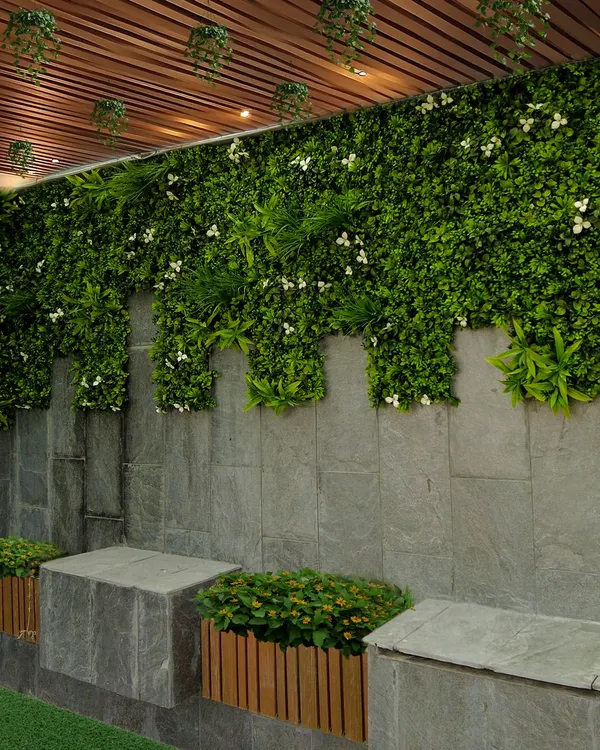 A vertical garden can completely change a space. Here, I used a combination of artificial greenery with small white flowers to cover a stone wall, creating a lush, maintenance-free feature that adds life and style under a slatted ceiling.