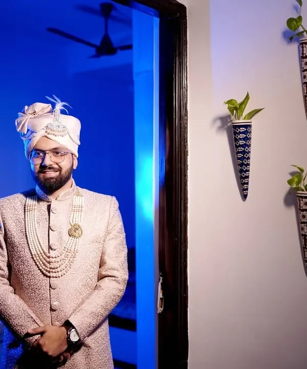 A stylish portrait of the groom in his wedding sherwani, ready for the big day. The blue backlighting adds a modern, cinematic touch.