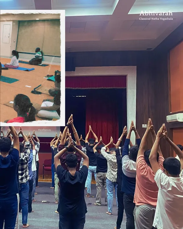 A large group of participants stand with hands in 'Namaskar', a gesture of reverence. My workshops are designed for everyone, creating a space to explore yoga as a tool for conscious living.