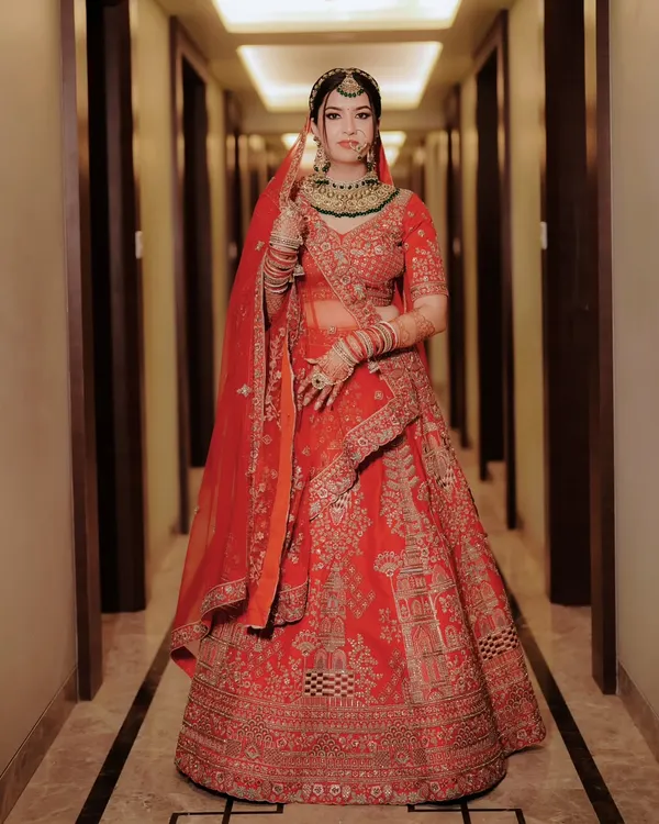 A breathtaking full length portrait of the bride in her magnificent red lehenga. This is a classic, regal shot that showcases the grandeur of a North Indian wedding.