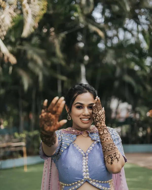A playful and happy bride at her Mehendi. The makeup is fresh and fun, with a pop of color on the eyes to match her vibrant Papa Don't Preach outfit.