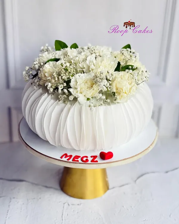 When a cake blooms like a flower vase. This unique design features delicate, pleated wafer paper details and is topped with fresh baby's breath and carnations for a stunning, modern look.