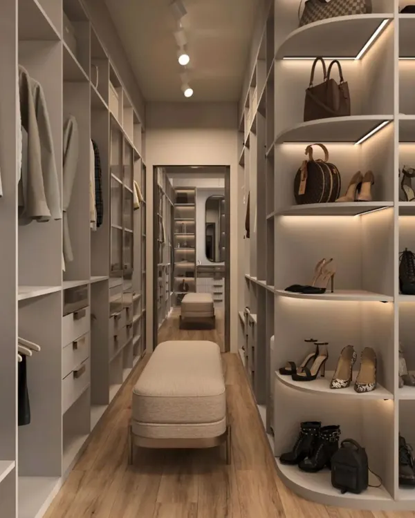A long, galley-style walk-in closet featuring ample hanging space and specialized curved shelving for shoes and bags. Integrated LED lighting under each shelf ensures every item is visible and beautifully displayed.
