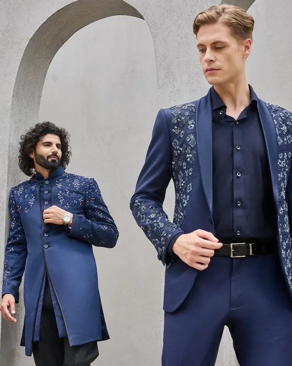 This single frame captures the essence of modern celebration. On the left, a bespoke Indo-Western sherwani with intricate shoulder embroidery for the 'dulhekabhai', and on the right, a contemporary embellished suit jacket. Both are crafted from the same premium navy fabric, showcasing how I create coordinated yet individual looks for your entire groom squad.