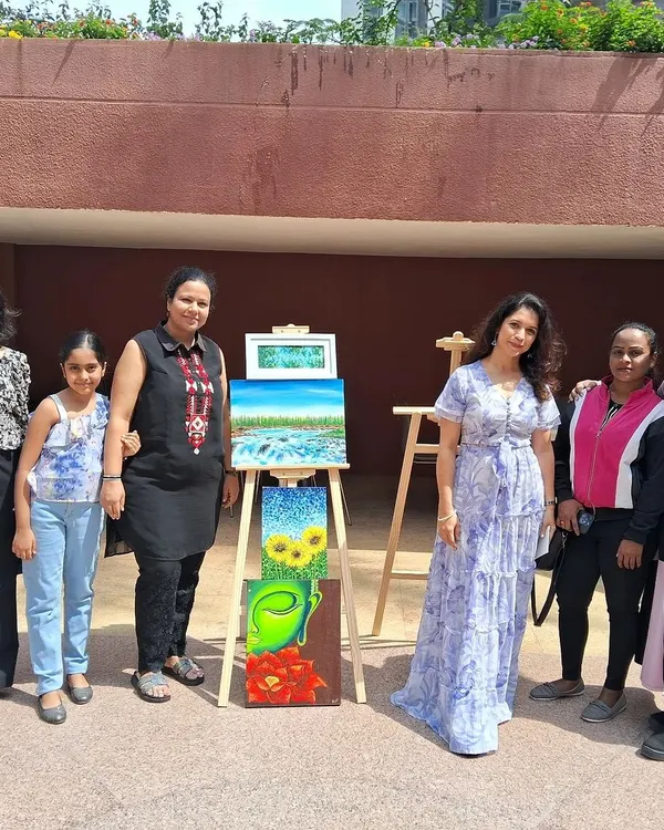 We love celebrating the results of a creative session. Here, a group of new artists, including families, proudly stands with our instructor Poonam and the beautiful paintings they created during a workshop.
