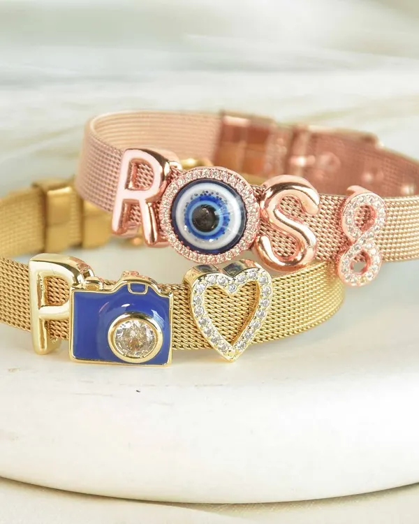 Don't miss out on these bracelets. You can customize them with your name, initials, and a wide variety of personal charms like this cute camera or evil eye.