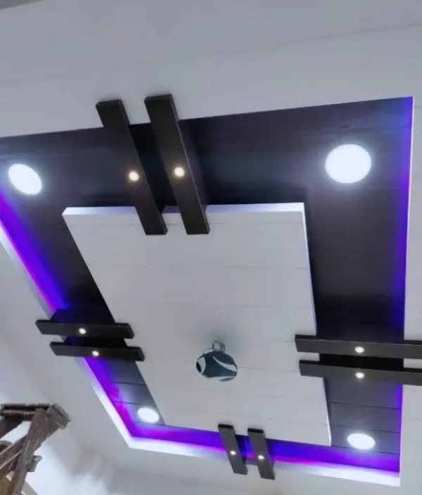 A modern PVC ceiling design with a dark wood finish. The purple cove lighting adds a cool, contemporary vibe, while the spotlights provide excellent functional light.