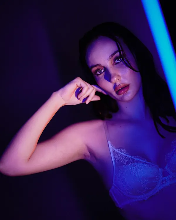 An artistic portrait using a sliver of blue light to create a moody and mysterious atmosphere. The focus is on the model's expression and the play of shadows.