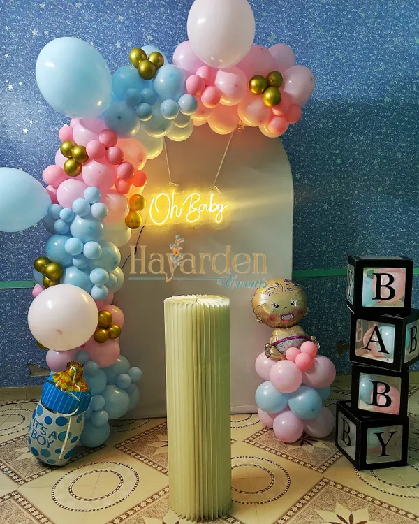 A lovely 'Oh Baby' gender reveal or baby shower setup. The pink and blue balloon arch, 'BABY' blocks, and themed foil balloons create a sweet and celebratory atmosphere.