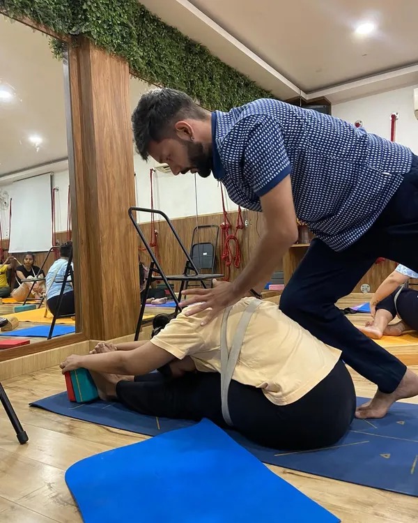 Here, I am providing a gentle adjustment in Paschimottanasana (Seated Forward Bend). The strap helps the student maintain a straight spine, while the blocks provide a target, ensuring a safe and effective hamstring stretch.