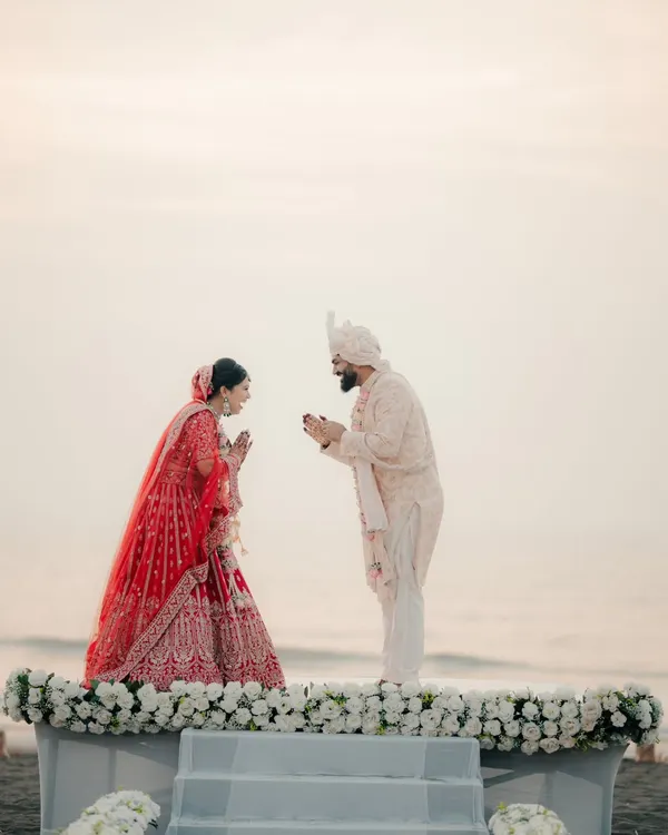 A beautiful moment from a beachside ceremony. The couple greets each other with a traditional namaste against the backdrop of the setting sun and the ocean.