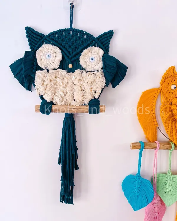 Meet the macrame owl family! This little guy is made with a beautiful teal cord and has a fluffy cream-colored body. He's perched on a natural wooden dowel and is ready to bring some wisdom and charm to your home.