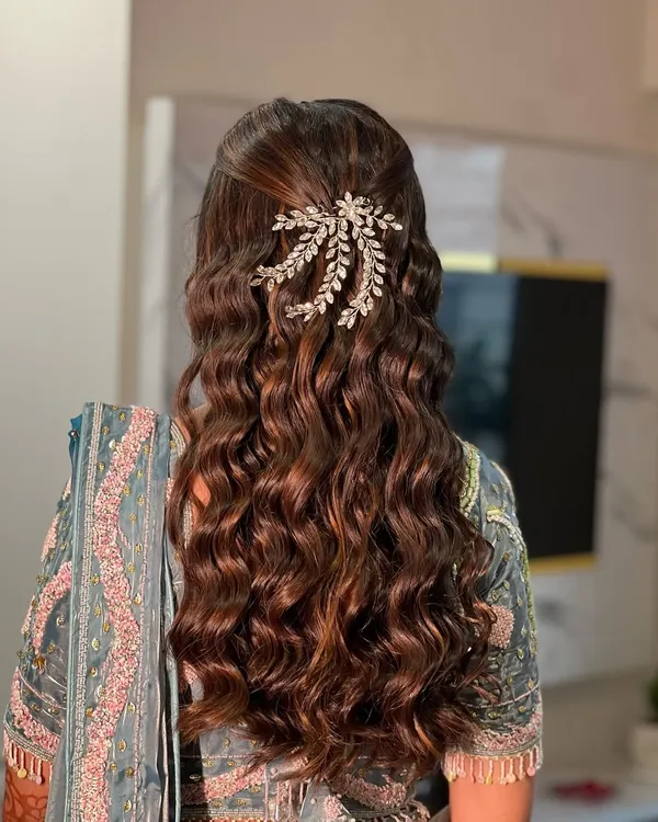 A beautiful example of a half-up, half-down hairstyle with soft, defined waves, perfect for an Engagement or Sangeet. The look is finished with a sparkling hair accessory.