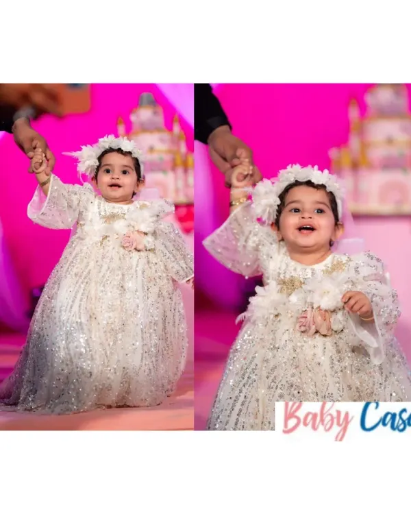 This is what we live for. Seeing a little angel light up the room on her big day. We designed this white sequin gown with bell sleeves and a floral headpiece to be as magical as her first steps and her sparkling smile. This is a perfect custom gown for a first birthday or a special family function.
