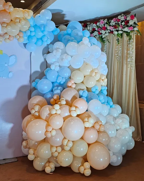 A massive, multi-colored balloon cascade in pastel shades of blue, peach, and white. This type of organic balloon sculpture can transform any corner into a stunning photo opportunity.