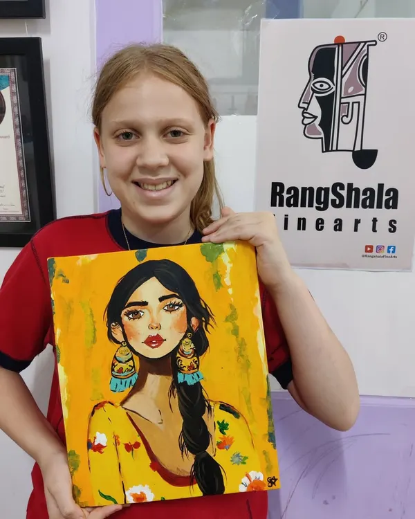 A young artist proudly displays her completed portrait, a testament to the skills and confidence gained in our kids' art classes. We guide each child to bring their unique vision to life on canvas.