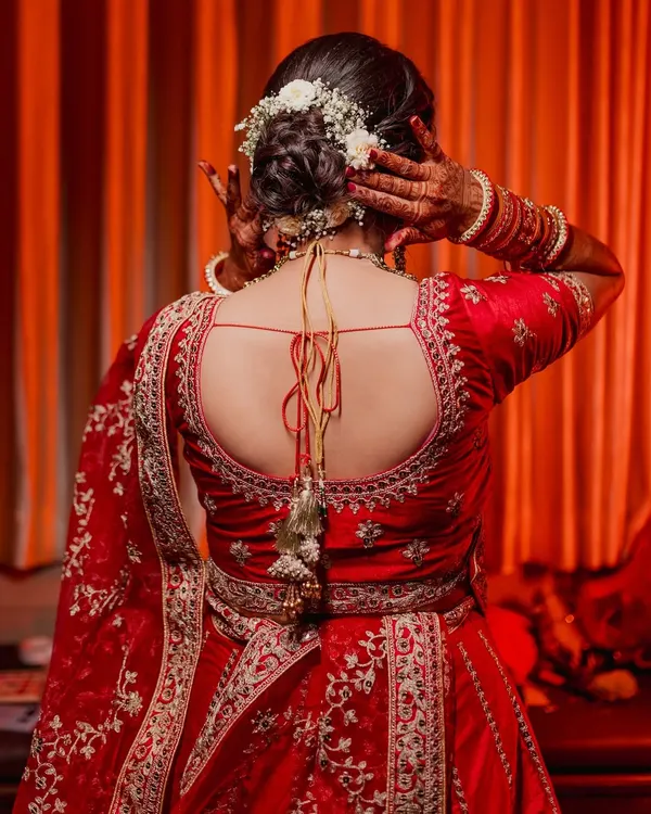 The back of a bride's outfit is often as stunning as the front. This shot highlights the intricate embroidery on her red lehenga and her beautiful floral hairstyle, details that deserve to be remembered.