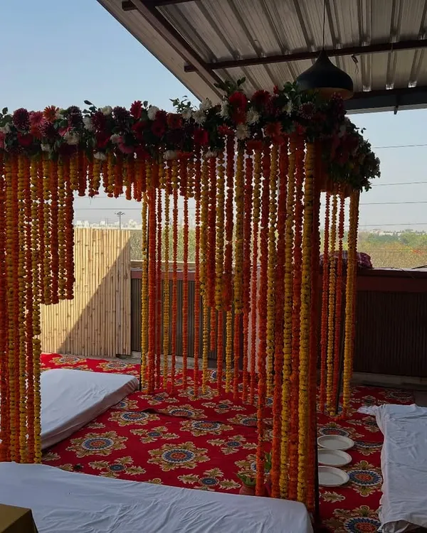 A classic wedding mandap for an outdoor ceremony. This setup uses a canopy of marigold strings and a mixed floral border, perfect for a traditional daytime wedding.