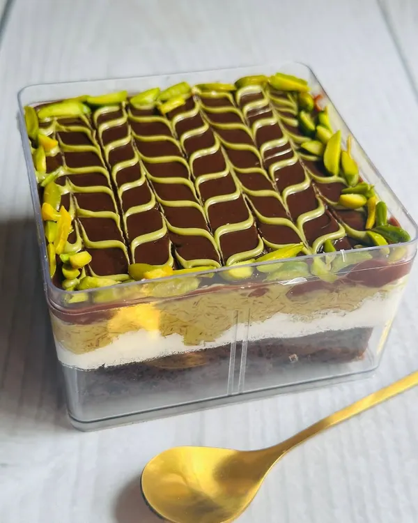 This is my viral Dubai Chocolate Pistachio Kunafa Tub. It features layers of rich chocolate cake, creamy cheese frosting, a crunchy pistachio kunafa layer, and a decadent milk chocolate ganache topping.