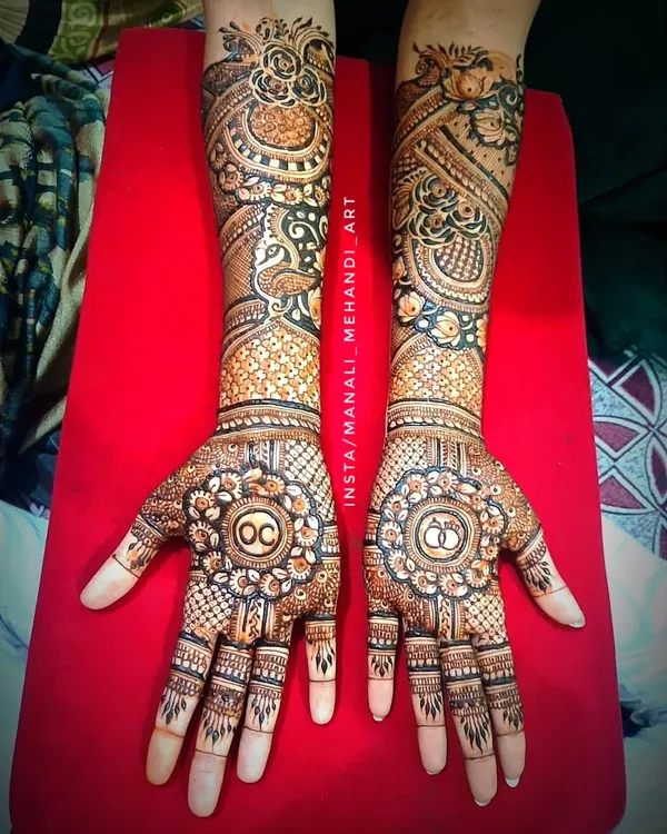 A full bridal-style mehandi for an engagement ceremony. This intricate design includes the couple's initials and engagement ring symbols, surrounded by peacock and floral patterns.