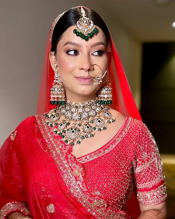 This is the kind of complete, stunning look we can create together. Notice how the oversized Kundan choker, matching jhumkas, and maang tikka perfectly complement the bride's red lehenga. It's a classic, royal look that is both elegant and timeless.