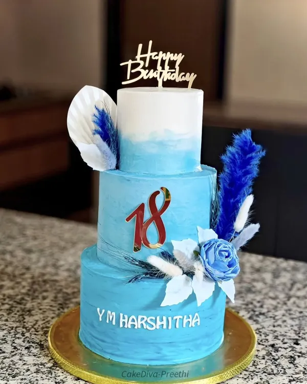Welcome to adulthood with this tall, three-tiered 18th birthday cake. The blue ombre design is decorated with dried grasses and a sugar rose, creating a modern and celebratory look.