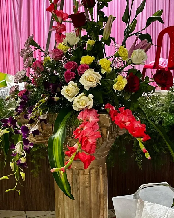 A close-up of a large, vibrant floral arrangement in a classic urn. This piece features a mix of roses, lilies, and orchids, showcasing the quality and variety of flowers I use to create stunning decor.