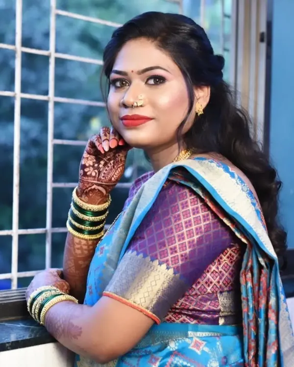 A beautiful Marathi bride ready for her special day. This look features a classic red lip, winged eyeliner, and a traditional nose ring, paired with a half-up hairstyle that is both modern and timeless.