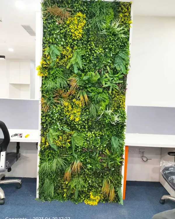A close-up of a dense and textured artificial green wall we installed in an office. The mix of ferns, grasses, and yellow-accented foliage creates a realistic and vibrant look without any maintenance.