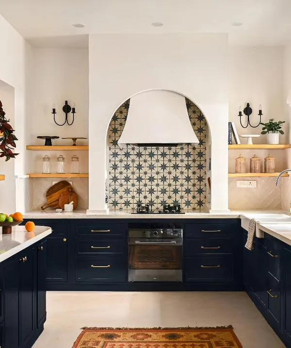 This is the baking kitchen from my Modern Spanish Home project, designed to be the heart of the home. I created distinct zones for every task, from the farmhouse sink under the window to the tall arched display cabinet. The deep blue cabinetry grounds the space, while the custom arched range hood serves as a stunning focal point.