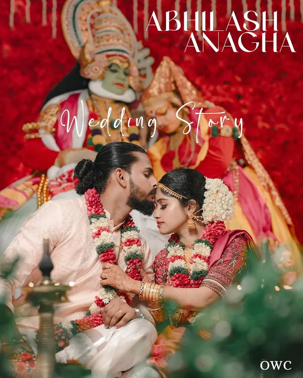 A beautiful moment from a Kerala wedding story, with the couple framed by Kathakali performers and vibrant red decor.