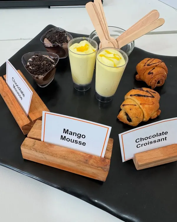 A platter showcasing some of our popular desserts. This selection includes rich Chocolate Mousse, seasonal Mango Mousse, and flaky Chocolate Croissants, perfect for a corporate meet.