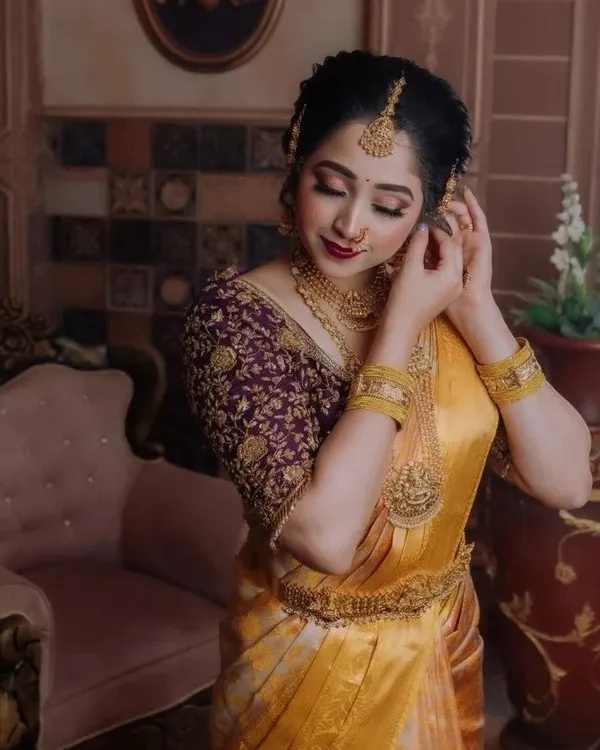A blouse can truly elevate a saree. Here you can see the intricate embroidery work on this custom purple blouse, perfectly complementing the golden yellow silk saree. We can create a unique design just for you.