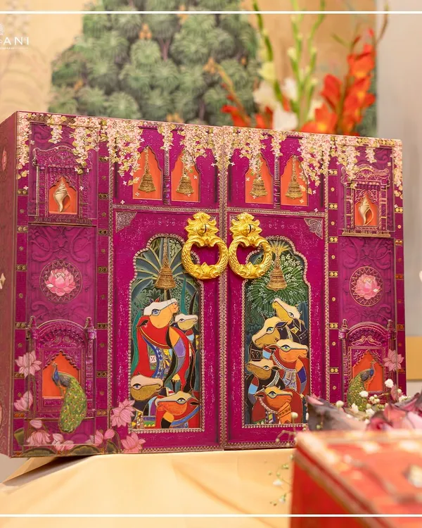 This magnificent invitation hamper is the centerpiece of my Pichwai collection. The doors, adorned with traditional art, open to reveal the wedding invitation, creating a dramatic and unforgettable unboxing experience for your guests.