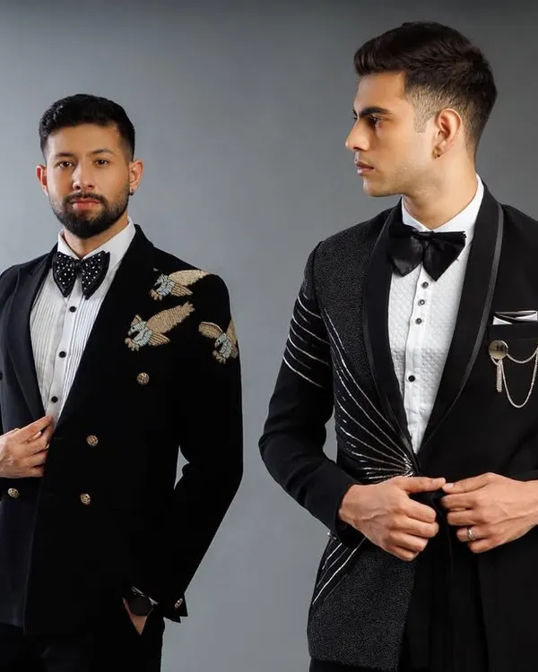 Two of our signature tuxedo designs. One is a double-breasted jacket with gold eagle embroidery on the shoulder, and the other is an asymmetrical design with metallic threadwork.