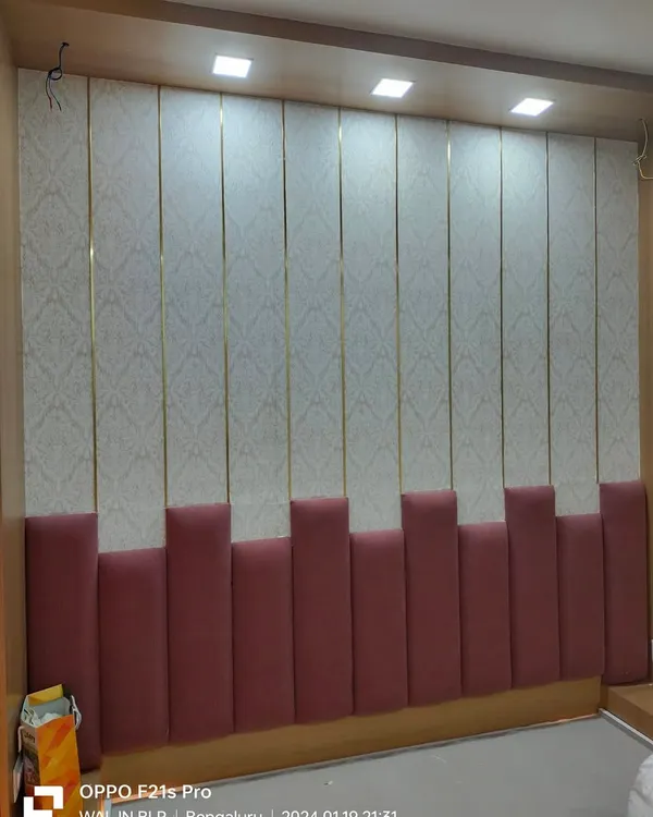 A full view of the custom upholstered headboard wall. The combination of a soft pink padded base and wallpapered upper panels with gold trim creates a sophisticated and complete look.