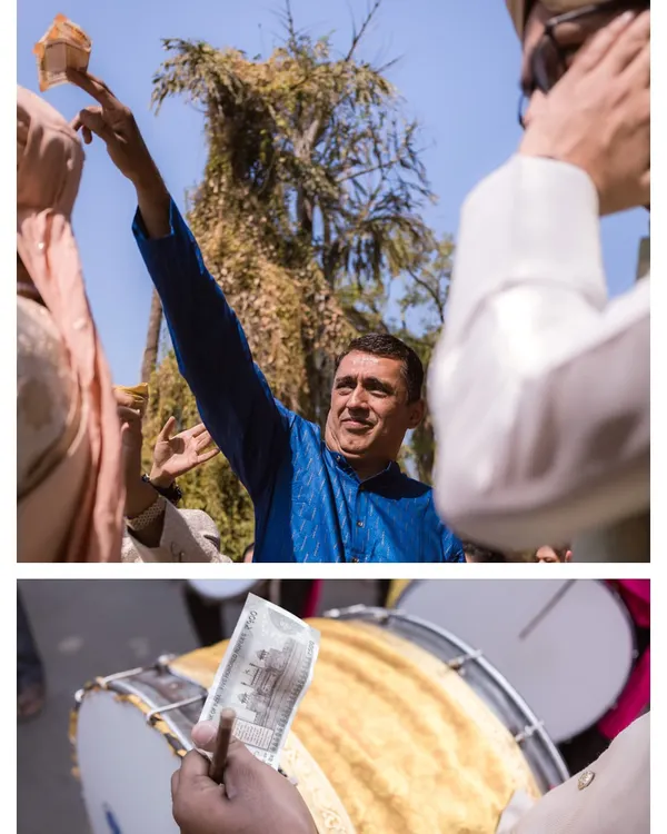 The energy of the Baraat. A guest joyfully throws money in the air, a traditional part of the celebration, while the dhol player keeps the beat.