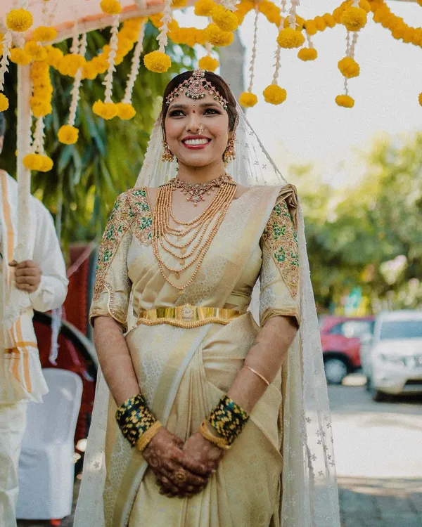 Our beautiful bride Jothi, glowing in a custom-curated off-white Kanjeevaram silk saree for her special day. We designed the entire look, from the hand-embroidered blouse to the traditional temple jewellery, to make her moment unforgettable.