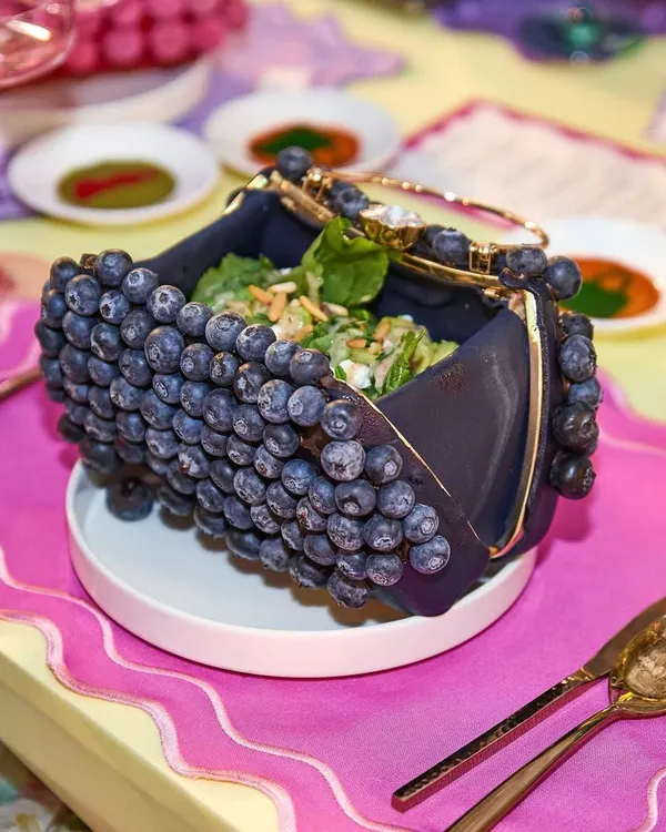 A Caesar salad served in a purse crafted entirely from blueberries. For a couture-inspired brunch, we believe in serving looks you can literally eat, transforming a classic dish into a fashion statement.