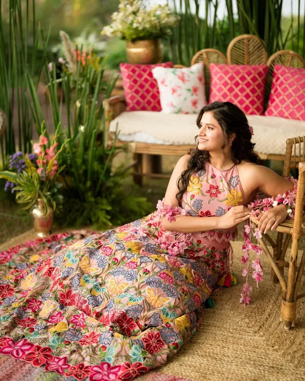 Yogita's Mehendi look was straight out of a fairytale. Surrounded by flowers, her fresh and radiant makeup with soft curls and a floral halter neck outfit created a truly dreamy and picturesque moment.
