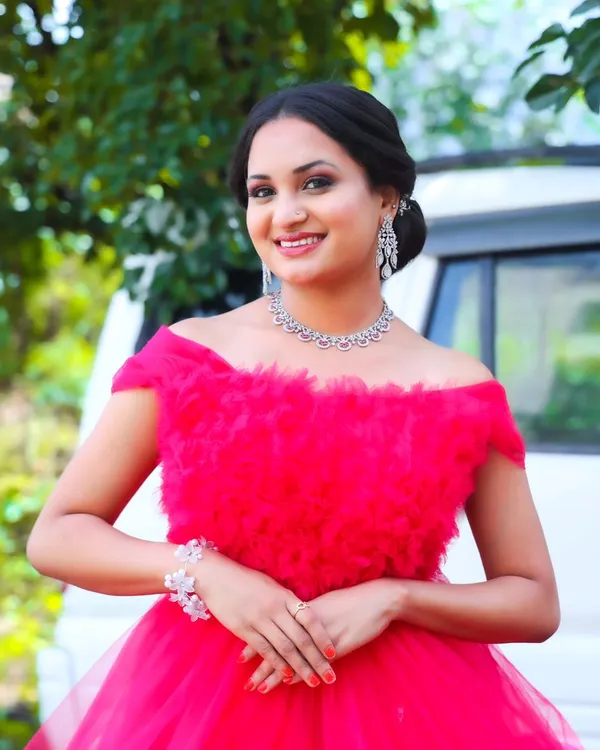A bright, happy smile from a modern photoshoot. The makeup is glamorous yet fresh, with smoky eyes and a nude lip, letting her natural beauty shine in this stunning pink gown.