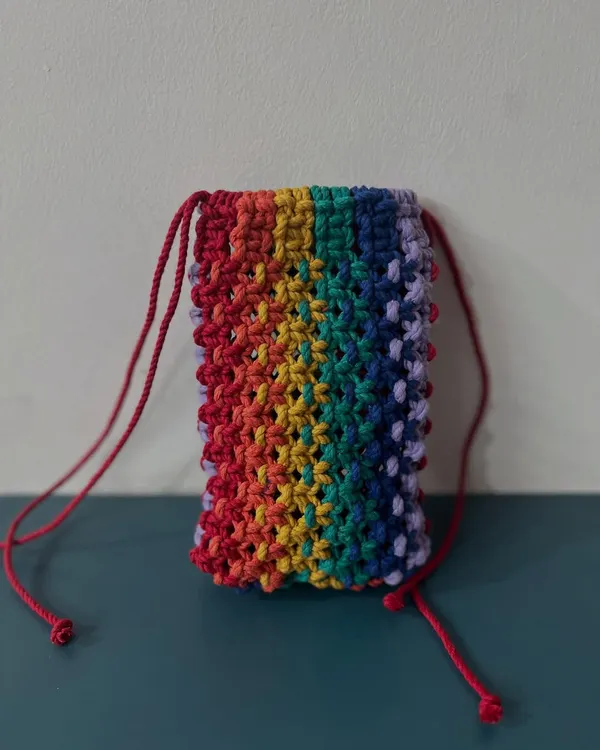 A vibrant rainbow-themed mobile pouch with a red drawstring. It's a cheerful way to protect your phone.