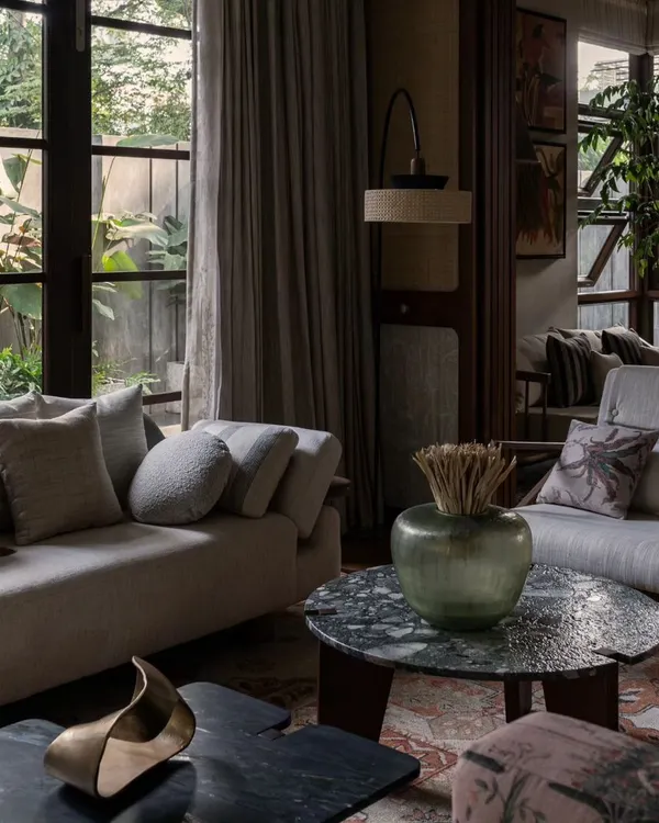 A cozy corner in our Pràna project, where textures and natural light come together. We mixed different fabrics, a unique green marble coffee table, and warm wood tones to create a comfortable and sophisticated living room design.