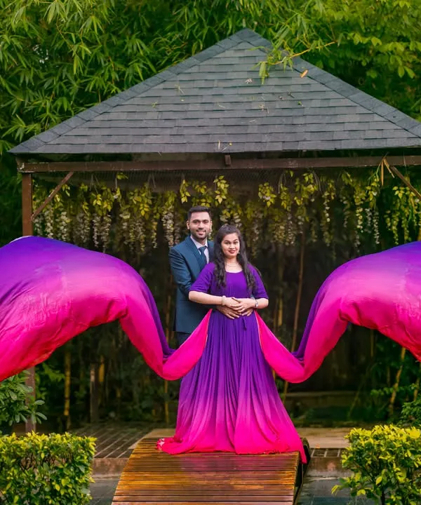 A perfectly symmetrical shot where the vibrant purple and pink gown creates a stunning wing-like effect. This is a great example of a bold, fashion-forward couple portrait taken at the gazebo in Elements Celebrate.