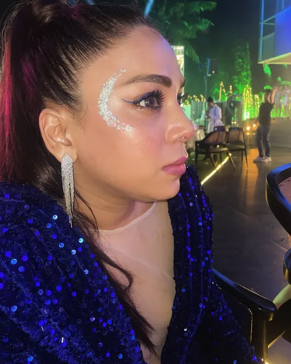 A classic festival look featuring a silver glitter crescent. This design beautifully complements the client's makeup and sequined jacket, perfect for a night of music and dancing.